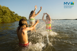 Drei Kinder planschen in einem See